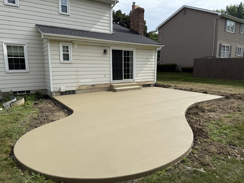 Curved concrete patio with steps behind residential home