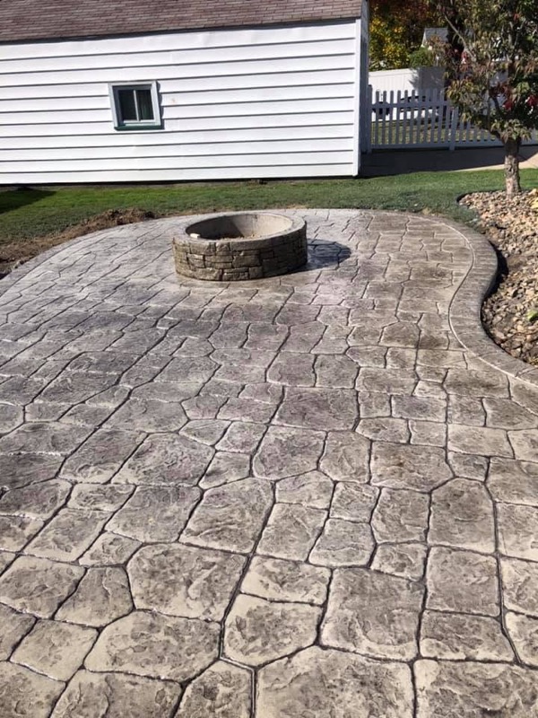Stamped concrete patio with stone fire pit - residential backyard